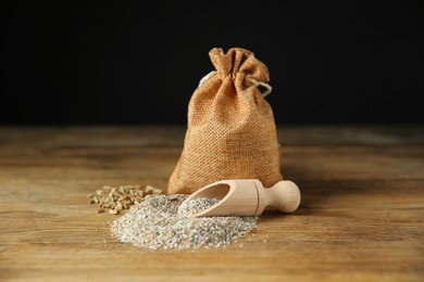 Photo of Pile of fresh rye bran, scoop and sack on wooden table