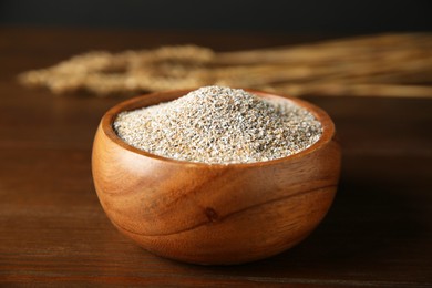 Photo of Fresh rye bran in bowl on wooden table, closeup