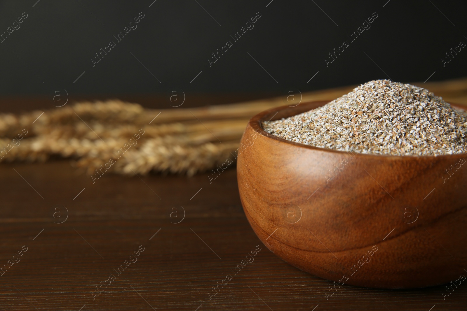 Photo of Fresh rye bran in bowl on wooden table, closeup. Space for text