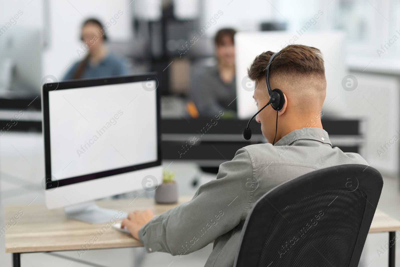 Photo of Salesman talking to client via headset at desk in office