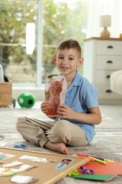 Creating vision board. Little boy with picture of cat on floor indoors