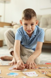 Photo of Little boy creating vision board with different pictures and other elements on floor at home