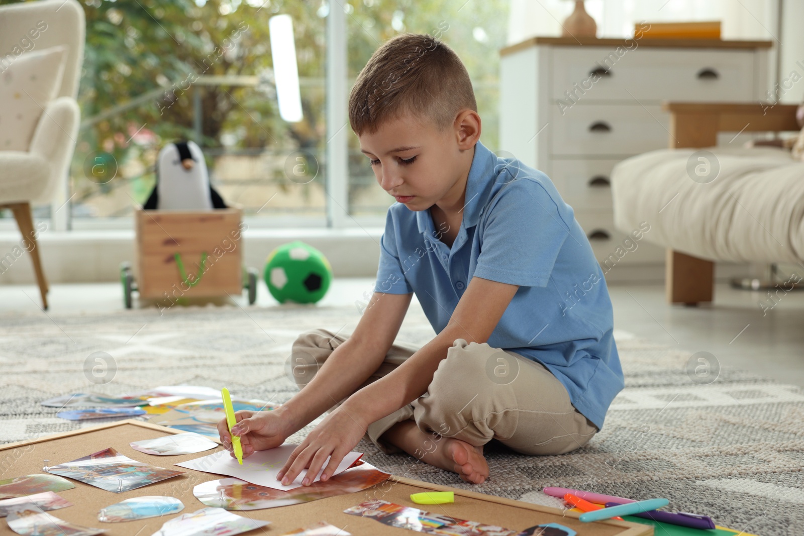 Photo of Creating vision board. Little boy drawing on paper indoors