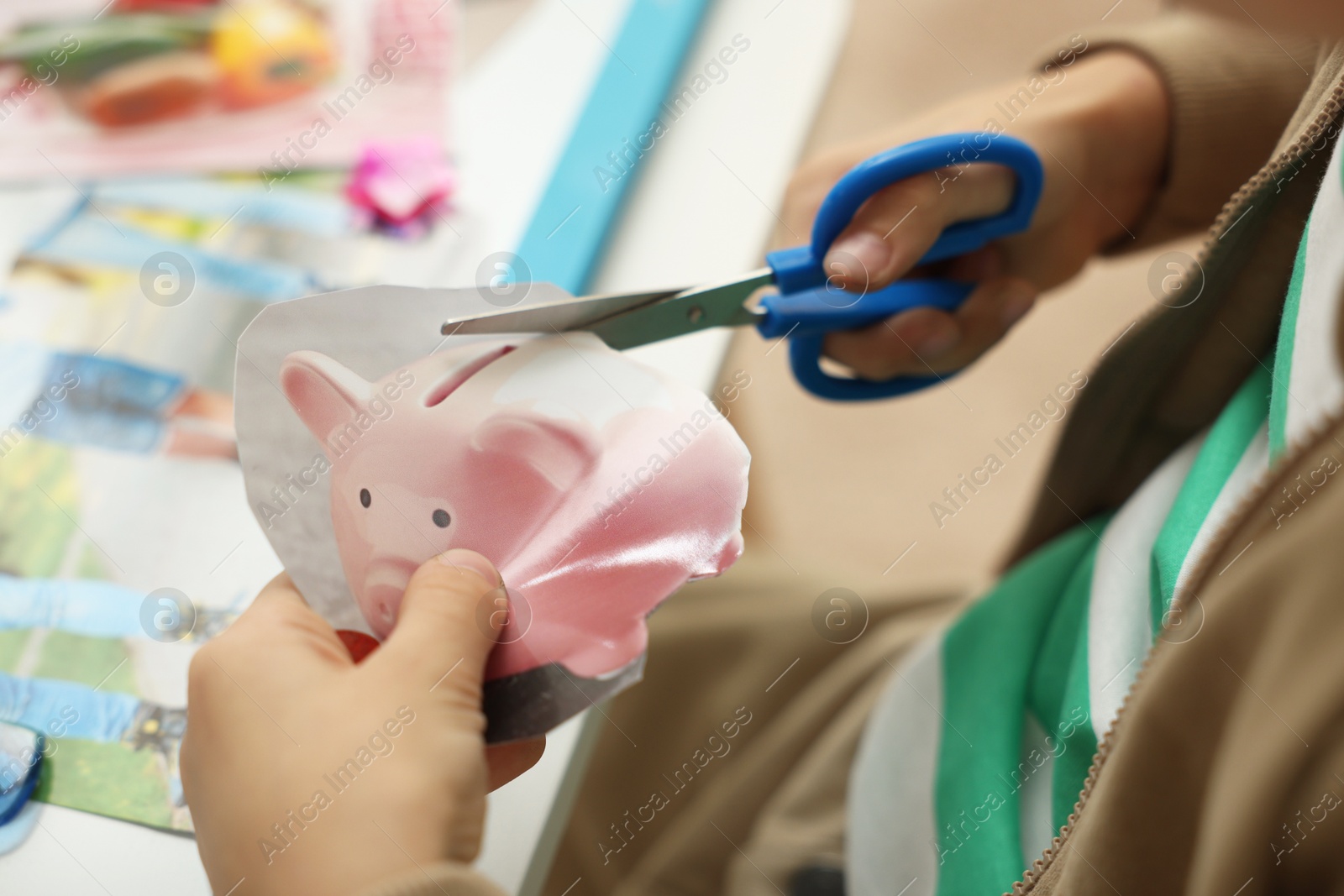 Photo of Creating vision board. Little boy cutting out picture at table indoors, closeup