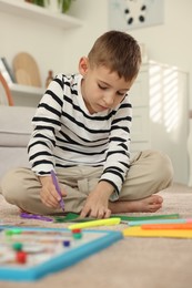 Photo of Creating vision board. Little boy drawing on card indoors