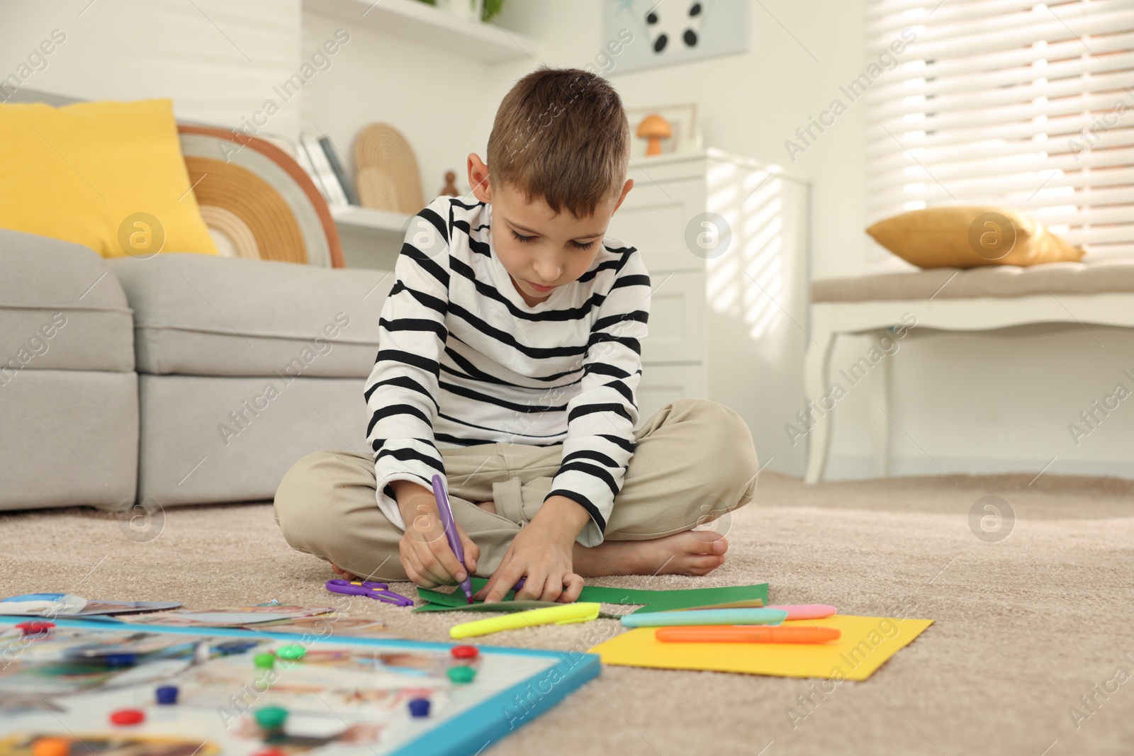 Photo of Creating vision board. Little boy drawing on card indoors