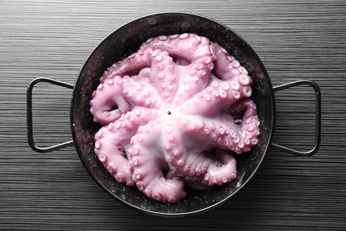 Photo of Fresh raw octopus in frying pan on dark textured table, top view