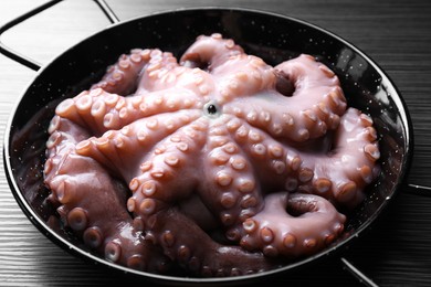 Photo of Fresh raw octopus in frying pan on dark textured table, closeup