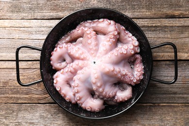 Photo of Fresh raw octopus in frying pan on wooden table, top view