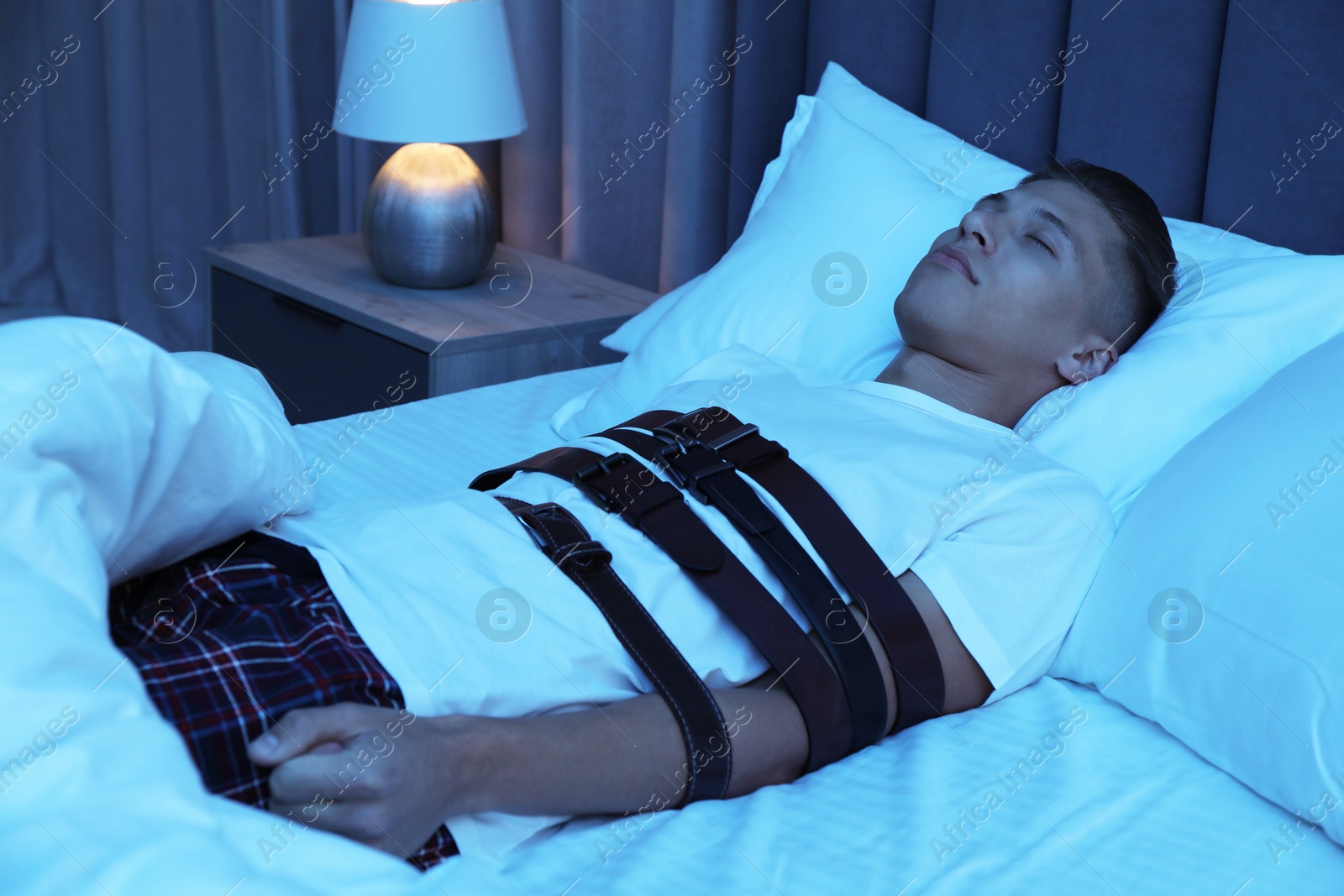 Photo of Sleepwalker fastened with belts lying on bed