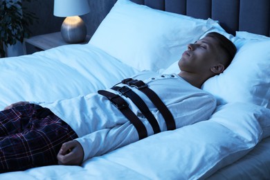 Photo of Sleepwalker fastened with belts lying on bed