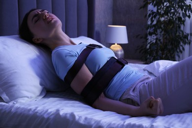 Photo of Sleepwalker fastened with belts lying on bed