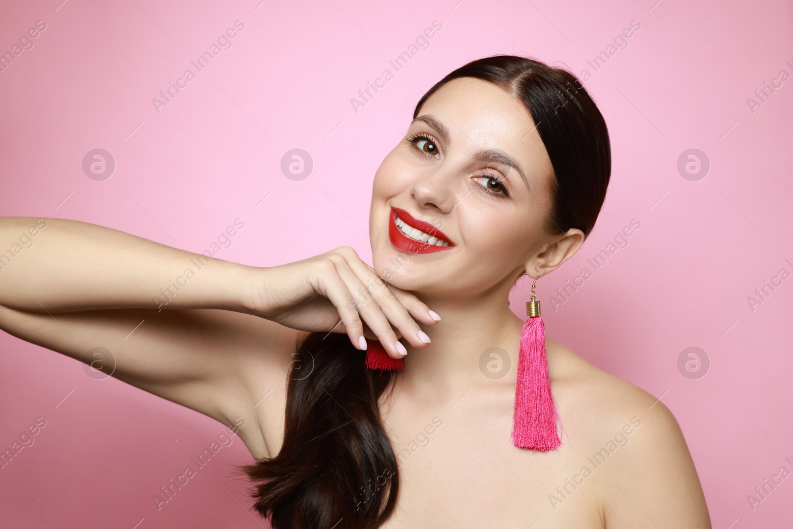 Photo of Beautiful young woman wearing stylish earrings on pink background