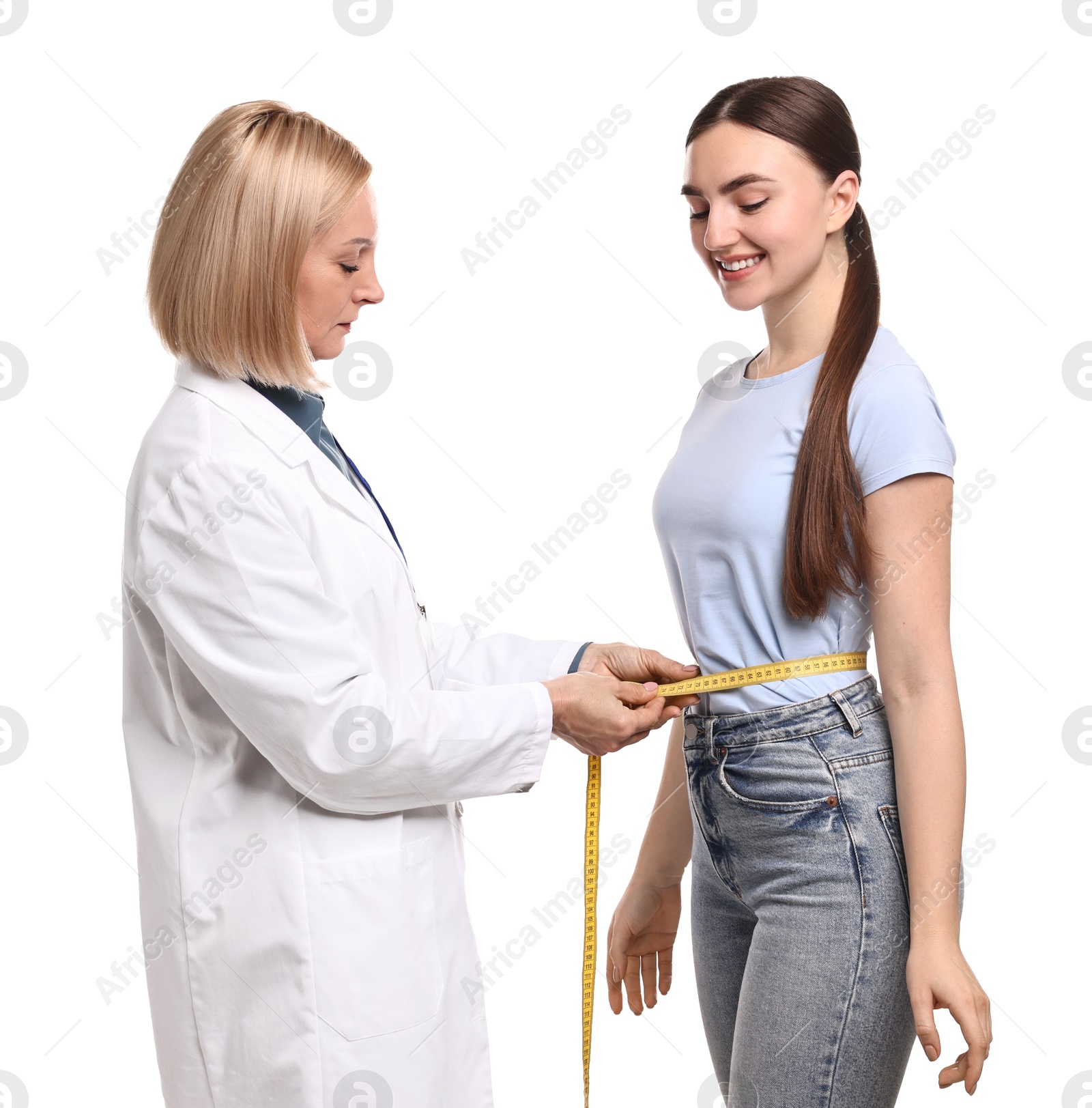 Photo of Happy woman lost weight. Nutritionist measuring patient's waist with tape on white background