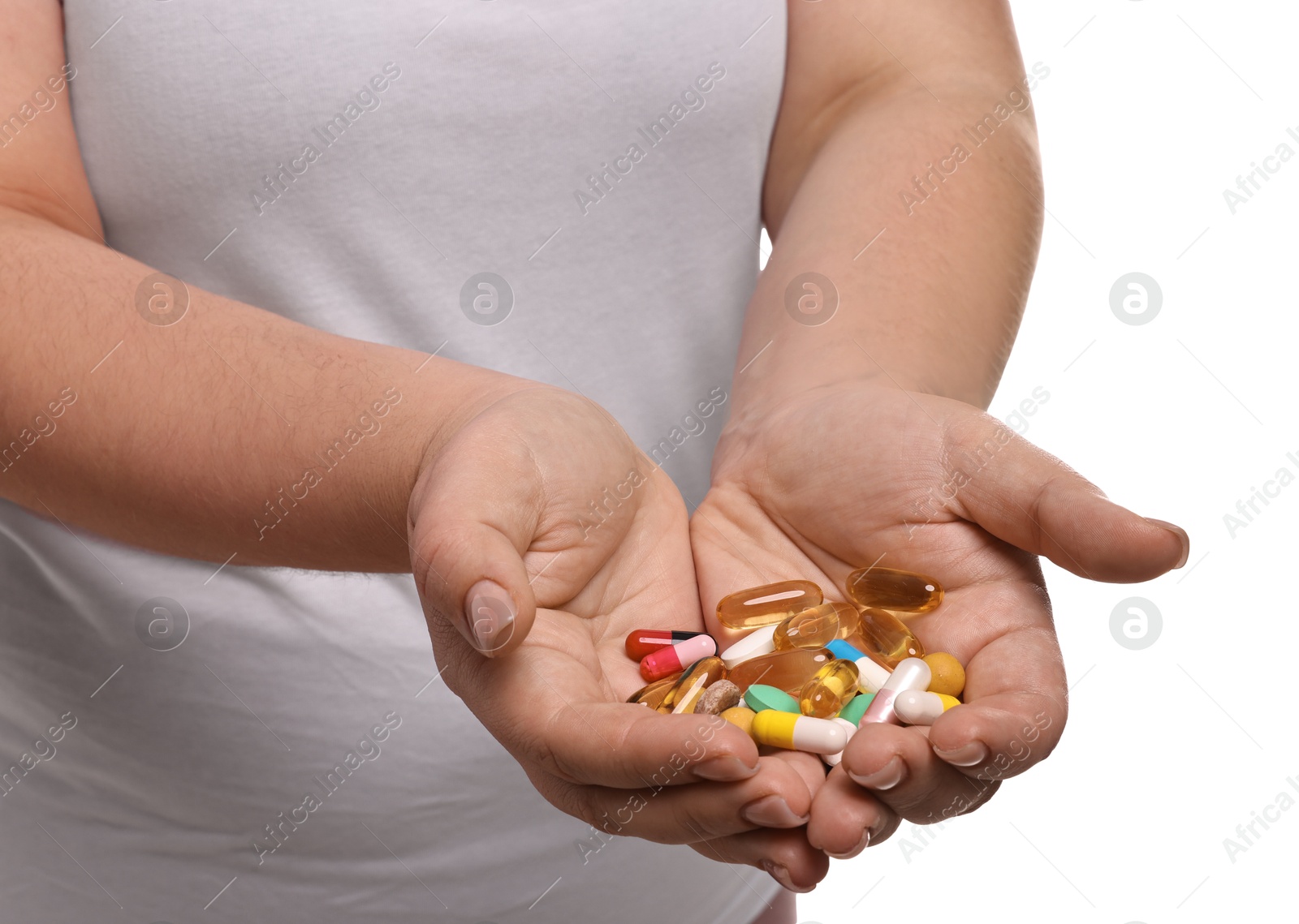 Photo of Plus size woman holding pile of weight loss supplements on white background, closeup