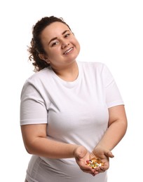 Photo of Happy plus size woman holding pile of weight loss supplements on white background