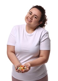 Photo of Happy plus size woman holding pile of weight loss supplements on white background