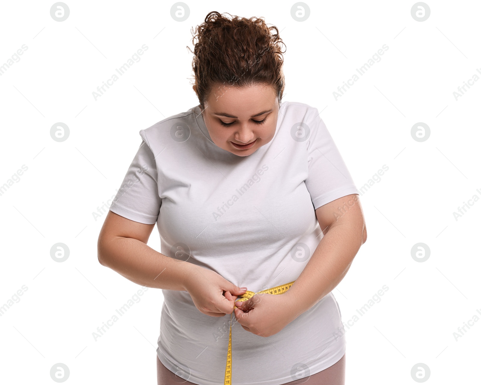 Photo of Weight loss. Plus size woman measuring waist with tape on white background