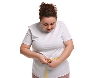 Photo of Weight loss. Plus size woman measuring waist with tape on white background