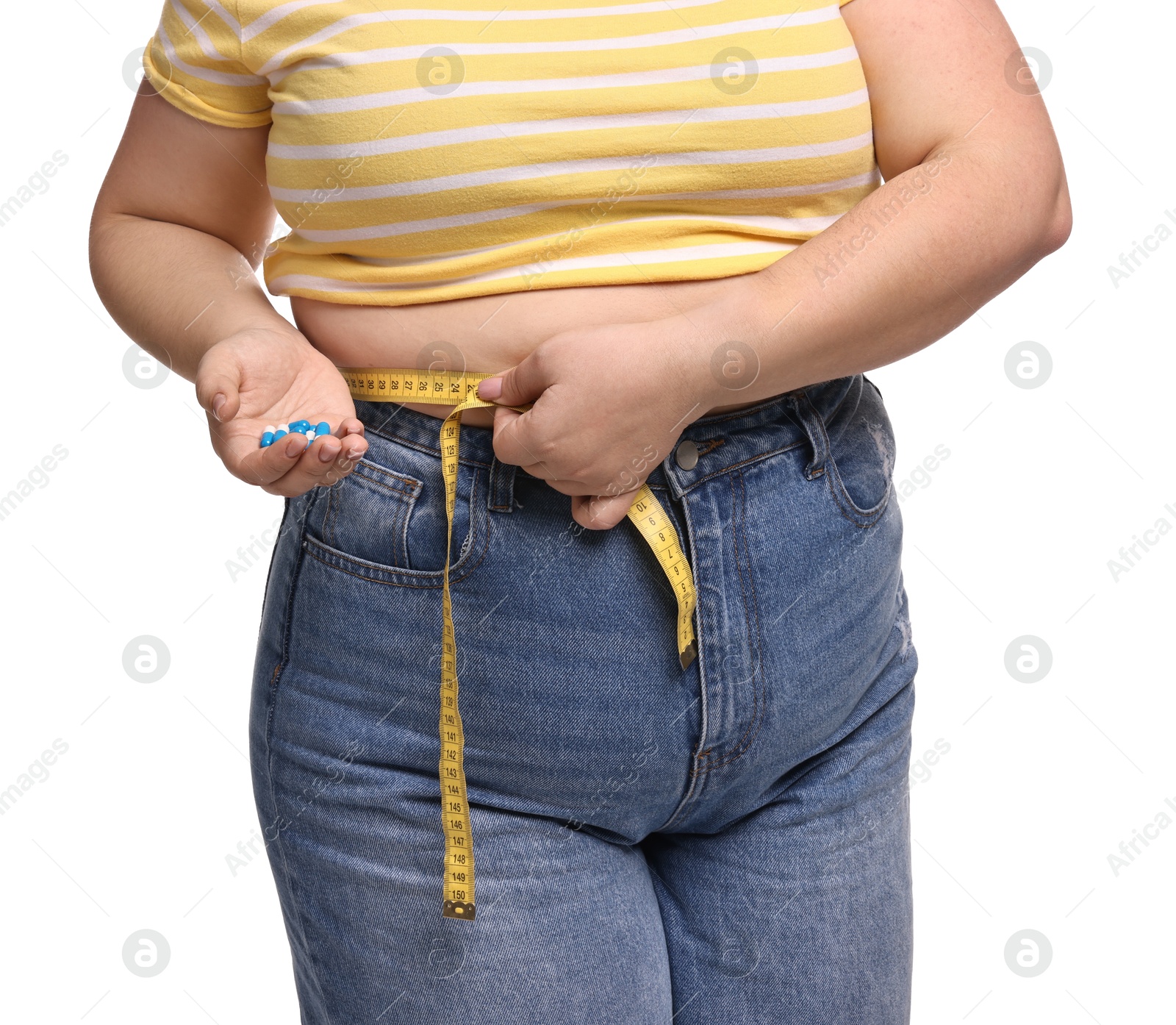 Photo of Plus size woman measuring waist with tape and holding pile of weight loss supplements on white background, closeup