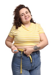 Photo of Happy plus size woman measuring waist with tape and holding pile of weight loss supplements on white background