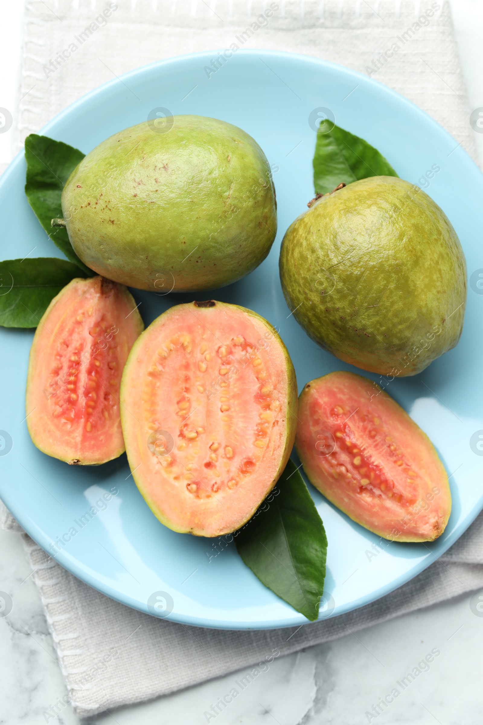 Photo of Fresh guava fruits and leaves on white marble table, top view