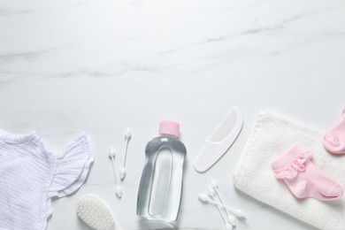 Photo of Baby oil, clothes and bath accessories on white marble background, flat lay. Space for text