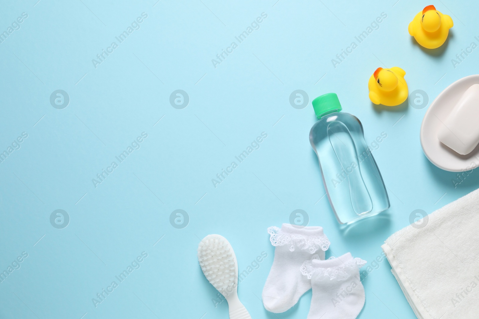 Photo of Baby oil and bath accessories on light blue background, flat lay. Space for text