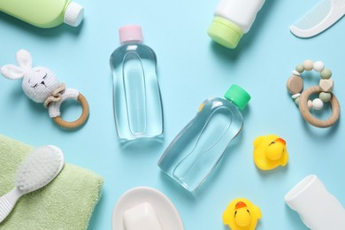 Photo of Baby oil and bath accessories on light blue background, flat lay