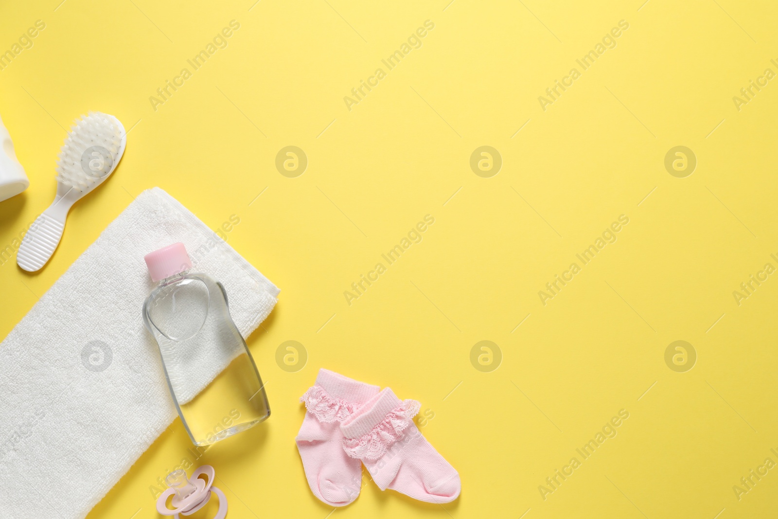 Photo of Baby oil and bath accessories on yellow background, flat lay. Space for text