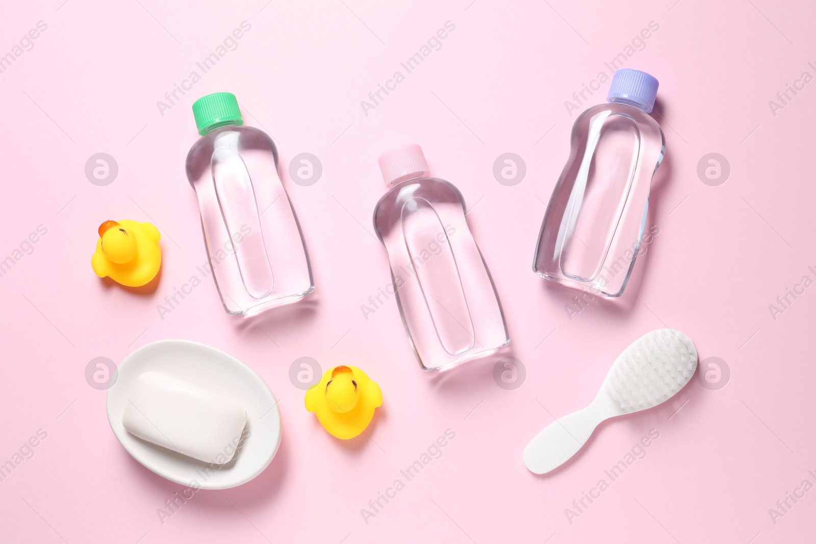 Photo of Baby oil and bath accessories on light pink background, flat lay