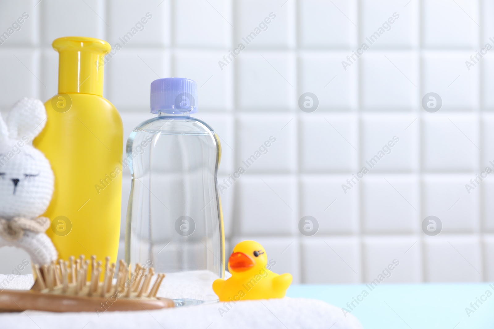 Photo of Baby oil and bath accessories on light table. Space for text