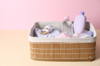 Photo of Baby oil and bath accessories in basket on color background