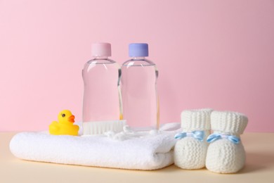 Baby oil and bath accessories on color background