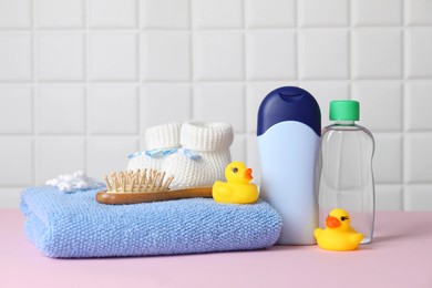 Baby oil and bath accessories on pink table