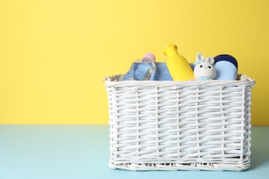 Photo of Baby oil and bath accessories in basket on color background. Space for text