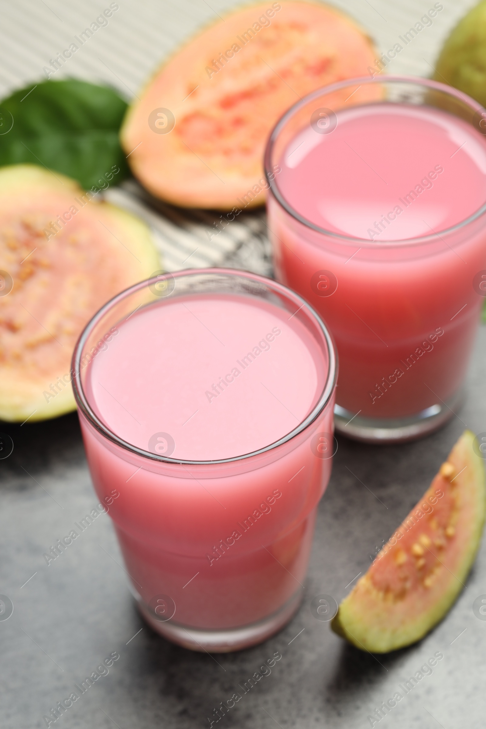 Photo of Refreshing guava juice and fresh fruits on grey table, closeup