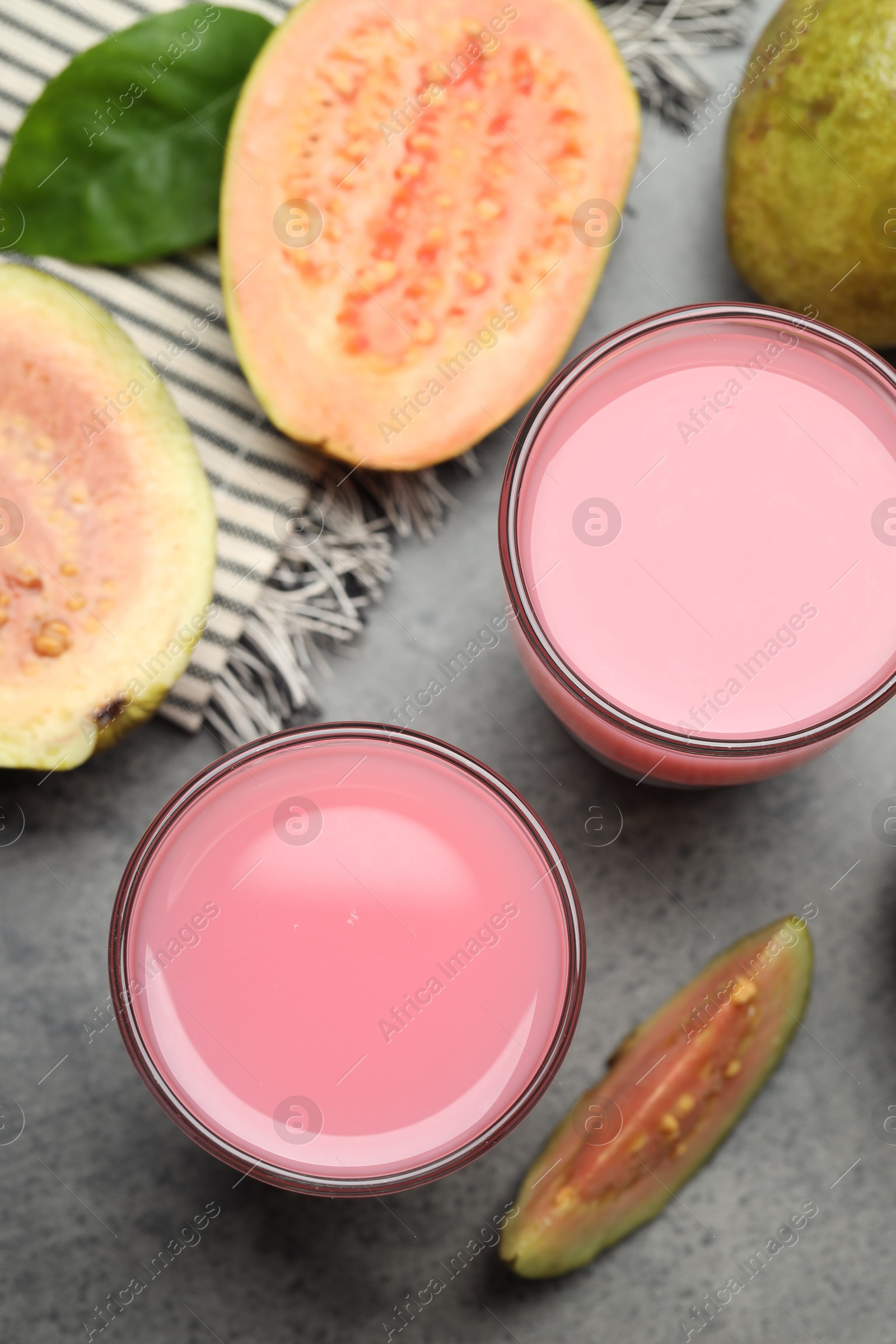 Photo of Refreshing guava juice and fresh fruits on grey table, flat lay