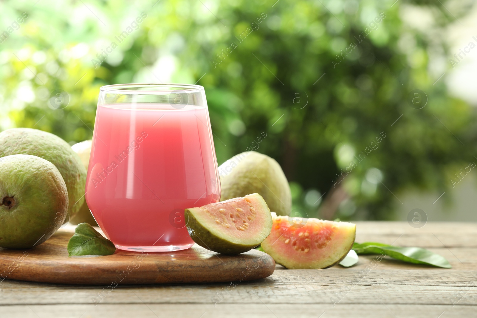 Photo of Refreshing guava juice and fresh fruits on wooden table, closeup. Space for text