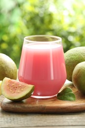 Photo of Refreshing guava juice and fresh fruits on wooden table, closeup