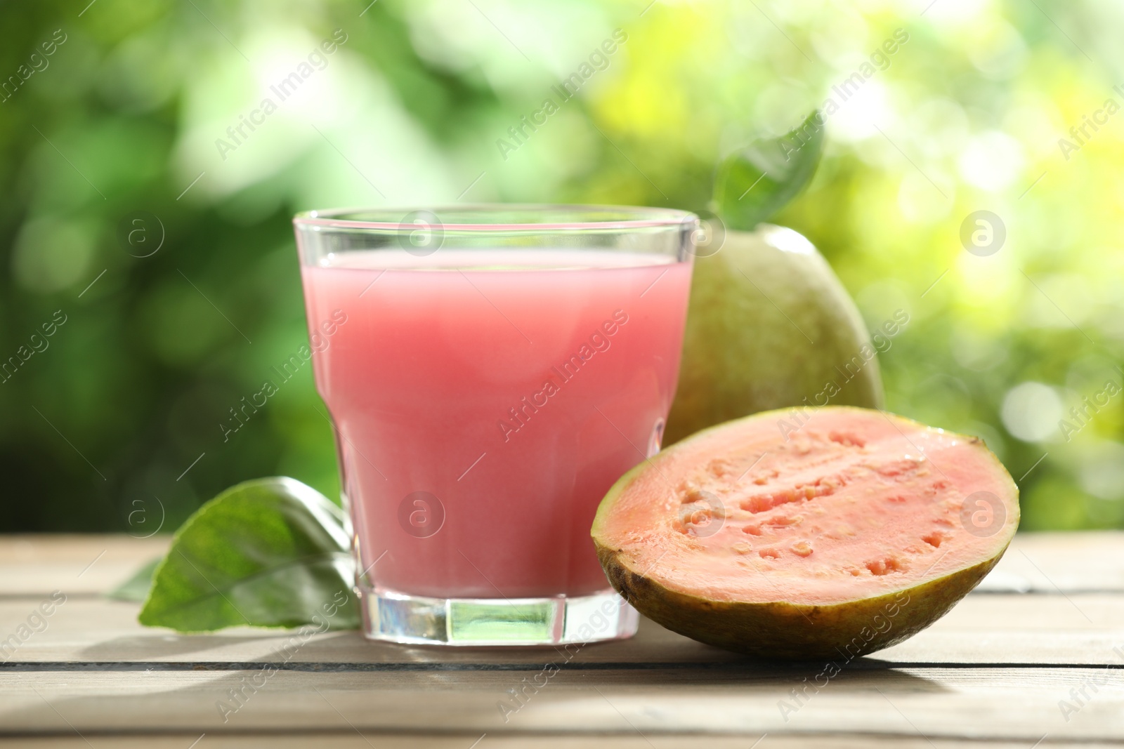 Photo of Refreshing guava juice and fresh fruits on wooden table, closeup