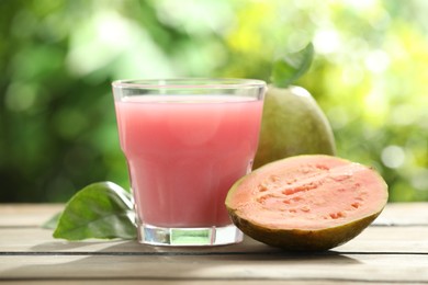 Photo of Refreshing guava juice and fresh fruits on wooden table, closeup