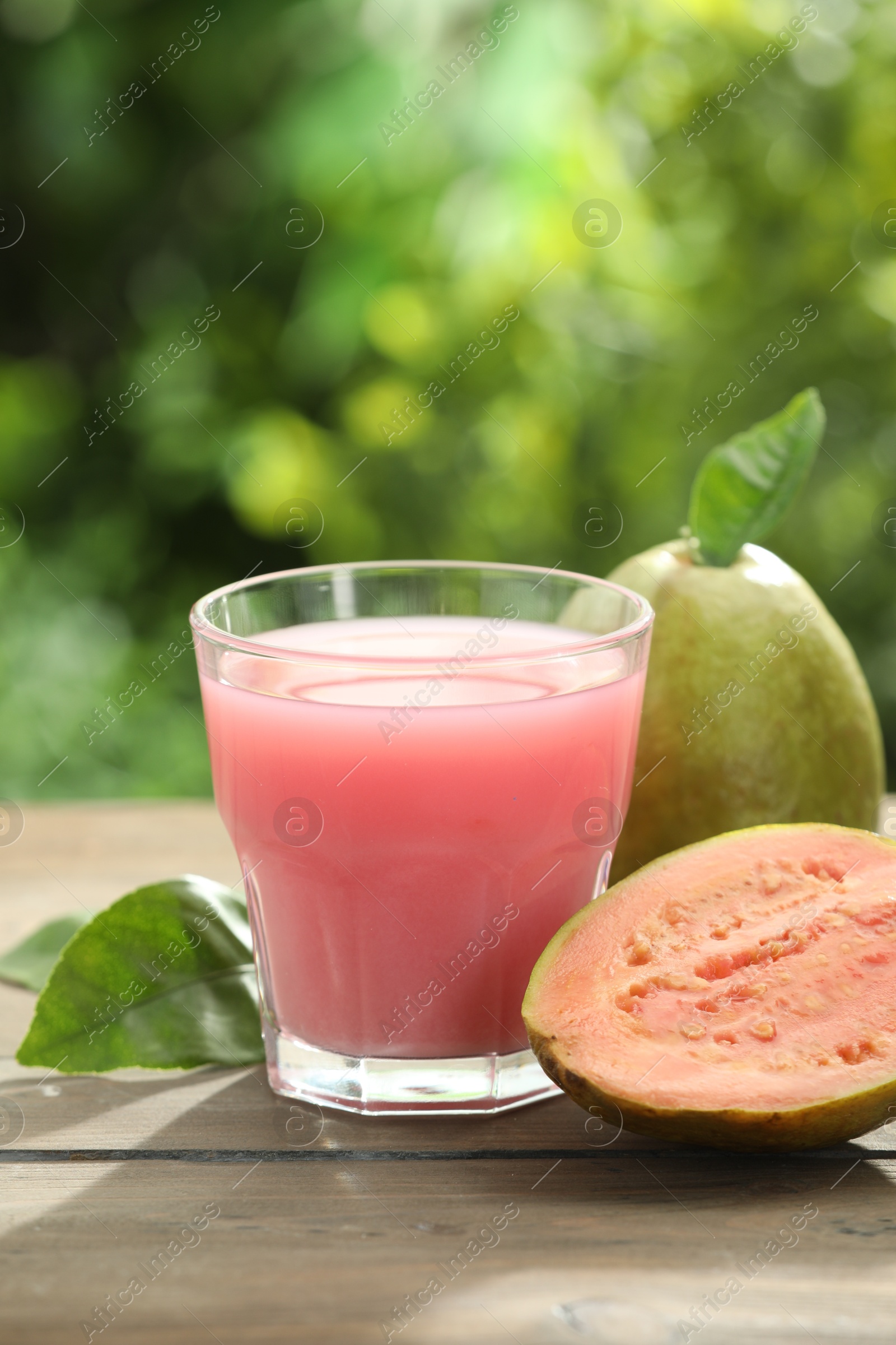 Photo of Refreshing guava juice and fresh fruits on wooden table, closeup