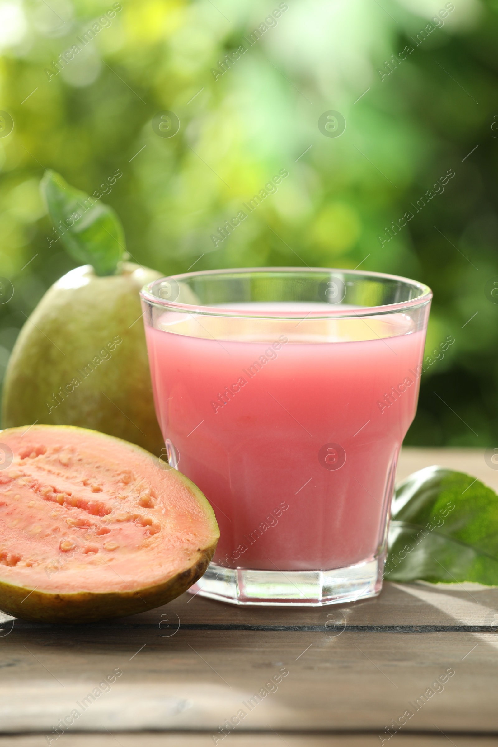 Photo of Refreshing guava juice and fresh fruits on wooden table, closeup