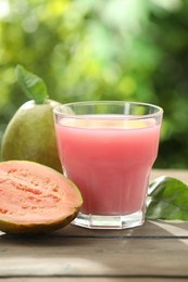 Photo of Refreshing guava juice and fresh fruits on wooden table, closeup