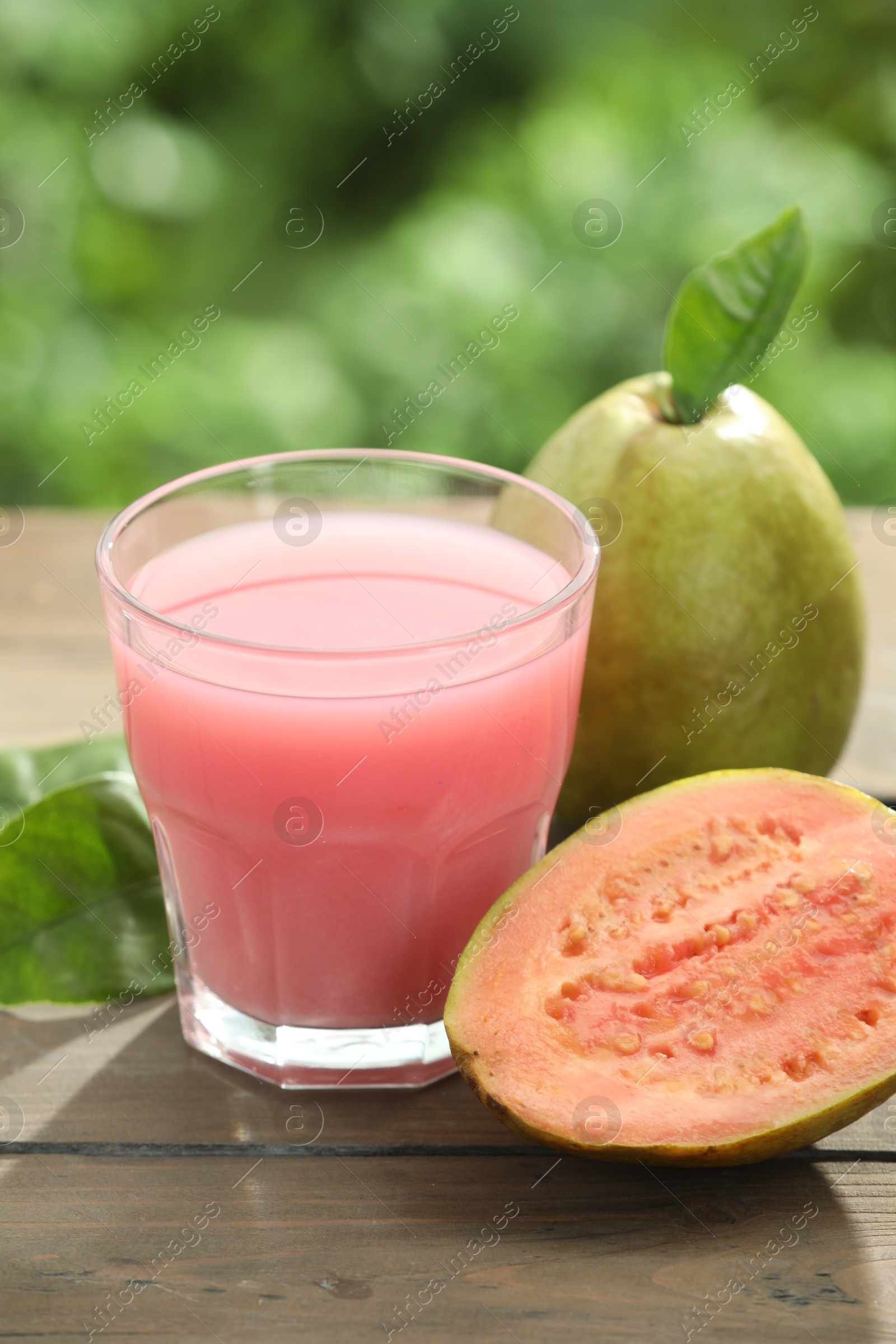 Photo of Refreshing guava juice and fresh fruits on wooden table, closeup