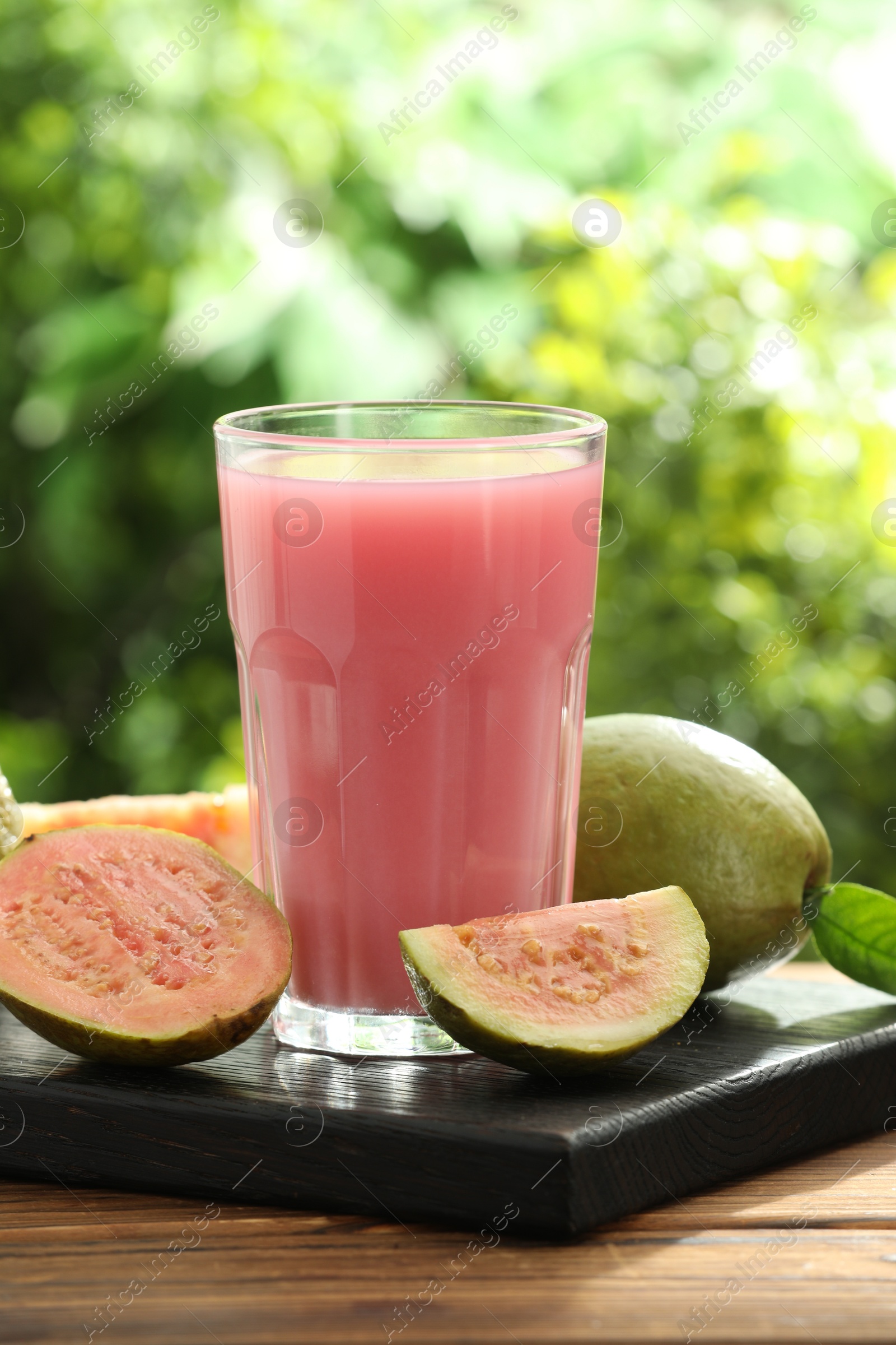 Photo of Refreshing guava juice and fresh fruits on wooden table, closeup