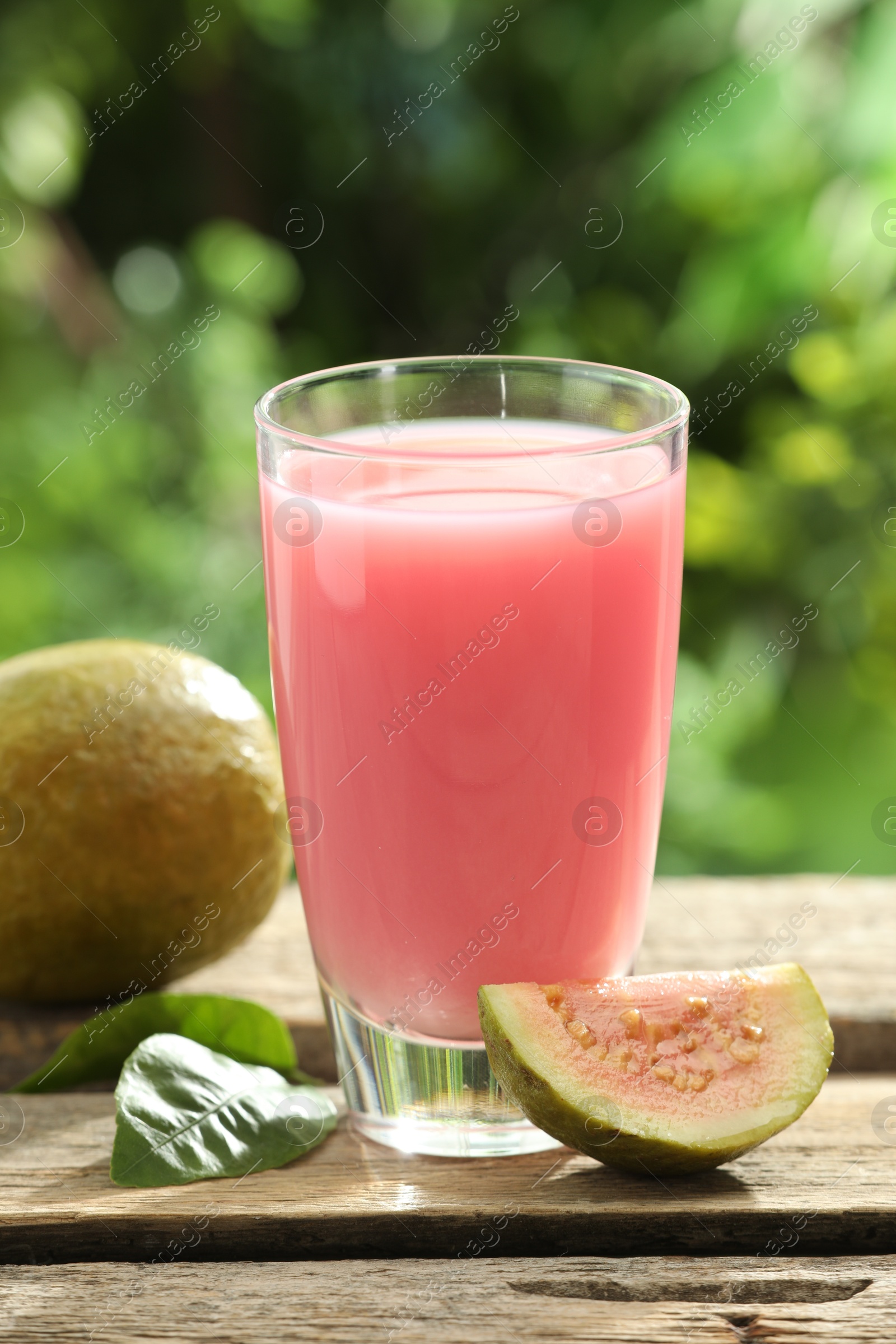 Photo of Refreshing guava juice and fresh fruits on wooden table, closeup