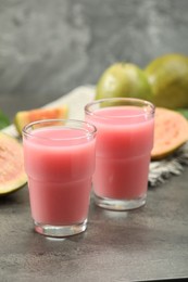 Photo of Refreshing guava juice and fresh fruits on grey table, closeup