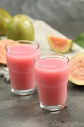 Photo of Refreshing guava juice and fresh fruits on grey table, closeup